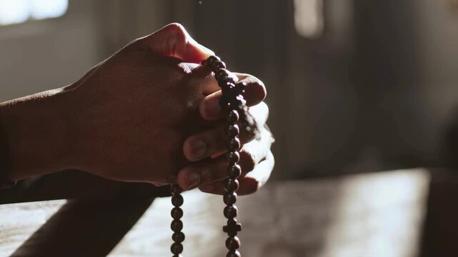 Close up of folded hands holding a rosary cross in deep prayer
