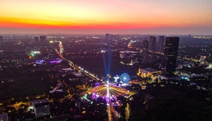 Fototapeta premium Aerial view of a vibrant city skyline at sunset with illuminated streets and buildings.