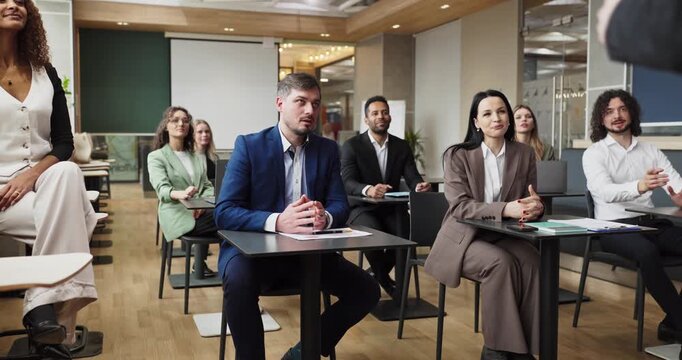 Audience attends seminar training and lecture. Bright classroom with professionals focused on presentation, listening and participating in meeting discussion. Clear message of corporate learning.
