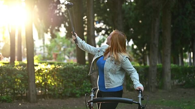 Young woman with mobility walker filming herself with action camera on selfie stick in park, user generated content creation, inclusive influencer lifestyle, accessibility and digital storytelling