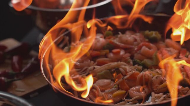 Close up of shrimp and vegetables cooking in a flaming wok