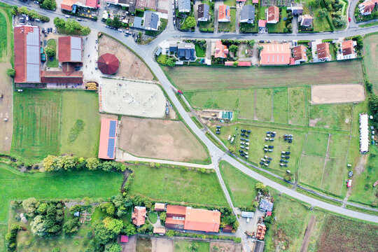 Aerial view of Reitclub In der Point Poxdorf featuring stables, outdoor riding arenas, and lush green fields in Poxdorf, Bayern, Germany.