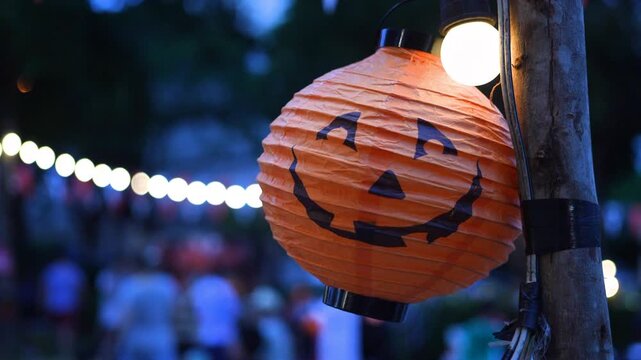 Halloween pumpkin lantern hanging on tree branch outdoors in daylight, spooky jack o lantern decoration with smiling scary face, holiday festive background, Halloween celebration and seasonal.