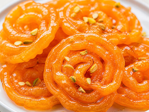 A plate of jalebi indian dessert topped with pistachios.