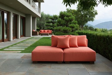 Fototapeta premium Modern orange modular outdoor sofa with cushions on stone patio beside manicured hedge and mountain view for terrace seating and contemporary exterior design