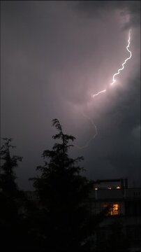 a vertical video of continuous lightning strikes flashing through a purple stormy night sky with branching electric bolts and thunder