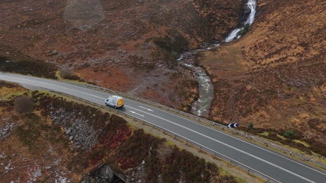 Van driving on scottish highlands road next to eas a' bhradain waterfall