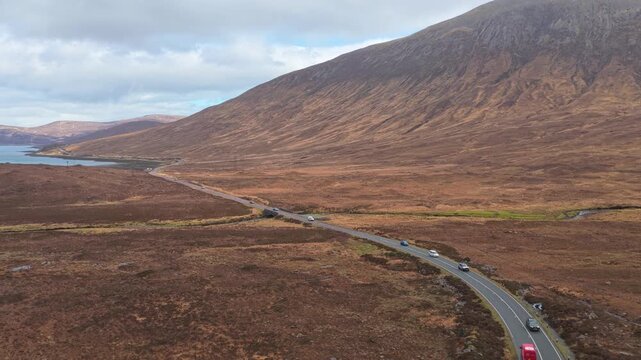 Cars driving on winding road in scottish highlands near eas a' bhradain waterfall