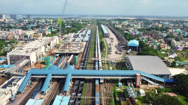 Aerial View of Indian Railway Station with Passenger Trains and Footbridge. Drone Shot of Busy Train Station Infrastructure and Railroad Tracks in City