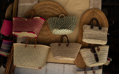 Fototapeta premium Colorful woven straw bags and baskets displayed on a wall in a local market during the day