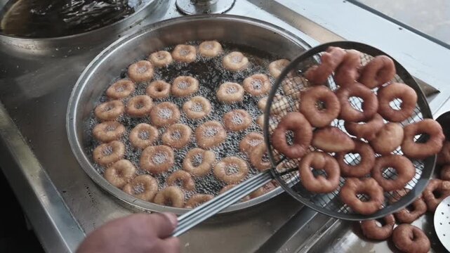 Fresh Turkish lokma dessert production at a street food stand. Golden fried dough sweets prepared in authentic local style.