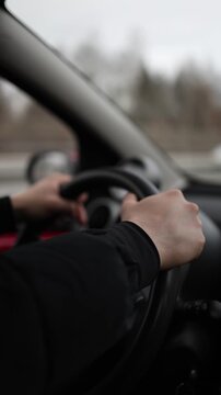 Vertical screen young driver learning vehicle control hands gripping steering wheel realistic automotive education scene with focused road training atmosphere