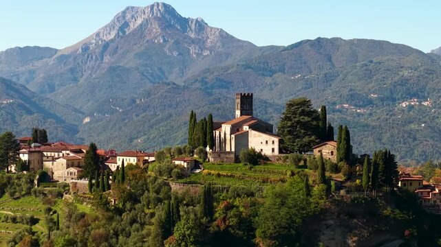 Barga Tuscany Aerial 4K. Drone cinematic sideways tracking shot revealing medieval Duomo cathedral on hill. Apuan Alps mountain range parallax scenery. Garfagnana valley travel. Part 2