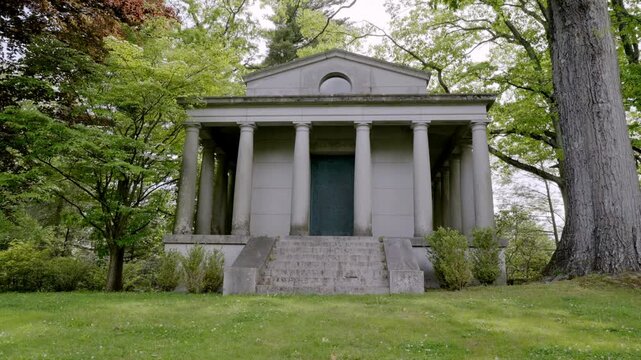 Classical Stone Mausoleum with Greek Columns in a Wooded Cemetery