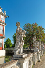 Obraz premium This vertical architectural composition shows a row of baroque sculptures at the castle bridge of Wolfenbüttel Castle. Blooming trees and clear blue sky enhance the historic atmosphere.