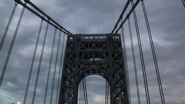 point of view of car driving over george washington bridge between fort lee new jersey and manhattan york heights (sunset night time cloudy suspension bridge)