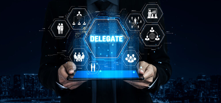 Businessman holding tablet displaying digital interface for delegation, teamwork, and collaboration with futuristic icons and graphics in a city background Sigmoid