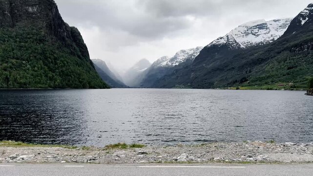 Beautiful Skjolden Norway Travel Video Showing Peaceful Fjord Water, Green Mountain Slopes, Snow Covered Peaks and Dramatic Cloudy Weather