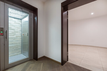 Modern design of the basement of a private house. A bright hall, a private elevator with  a glass door. © Alhim