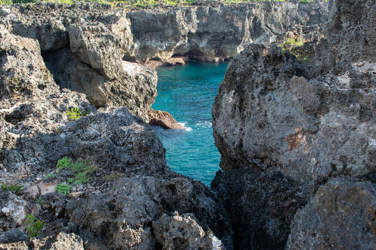 the texture of the steep limestone or volcanic rock formations with blue sea water
