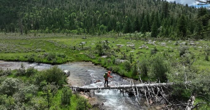 Woman walking on a one plank bridge in high altitude mountains