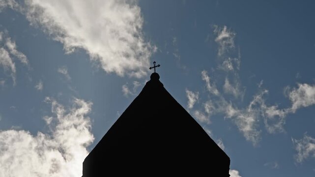 Church Steeple Silhouette Featuring a Majestic Crucifix Against Moving Clouds on a Sunny Day Perfect for Spiritual Themes and Religious Cinematic Background Footage for Faith Based Media Projects