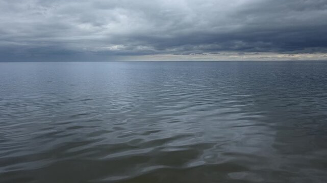 Video of a large lake with small waves reflecting a blue-gray cloudy sky
