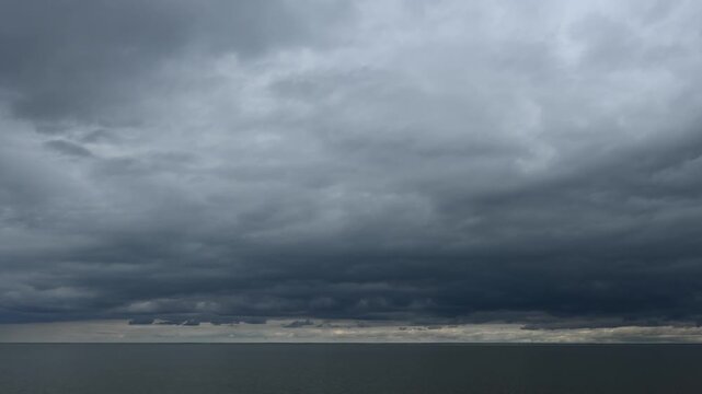 Video of a large lake with stormy clouds and occasional seagulls flying above a calm lake that is reflecting the sky
