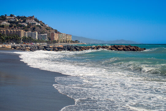 Stormy Mediterranean Sea with deep blue waves crashing on the sunny beach in Almunecar, Andalusia, Spain.