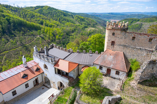 Visitors explore the ruins of Boskovice Castle in Czechia. The structure offers a view of green forests and hills under a clear sky. The area attracts tourists and history lovers alike.
