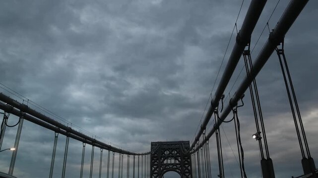 point of view of car driving over george washington bridge between fort lee new jersey and manhattan york heights (sunset night time cloudy suspension bridge)