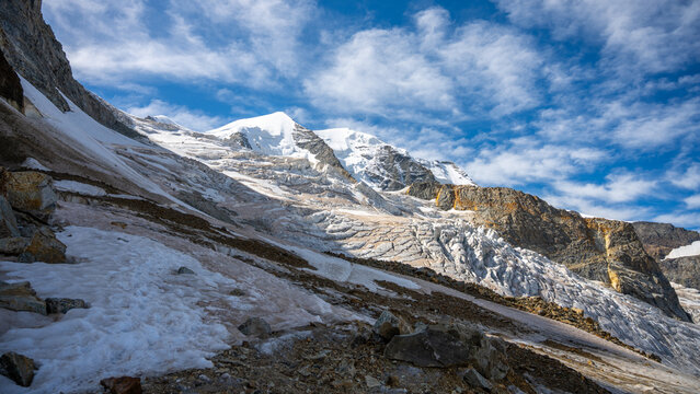 Piz Palu rises majestically in the Swiss Alps, showcasing its snowy peaks and glacier. The clear blue sky contrasts with the dramatic mountain landscape, perfect for alpine adventures.