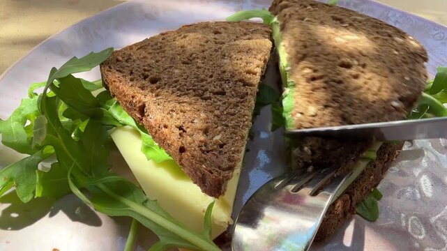 Eating cheese sandwich with organic brown bread with knife and fork