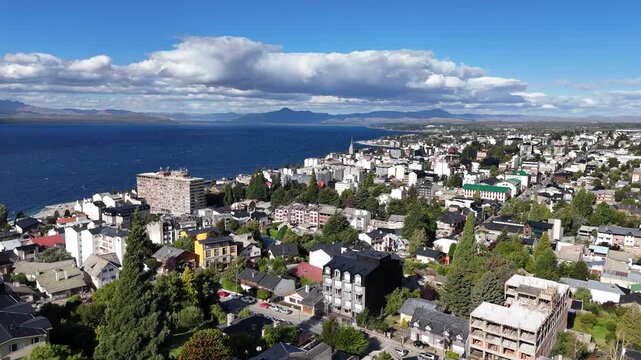 Aerial panoramic view of the alpine city of San Carlos de Bariloche and Nahuel Huapi Lake in Patagonia, Argentina. The picturesque town features a cathedral and is surrounded by mountains.