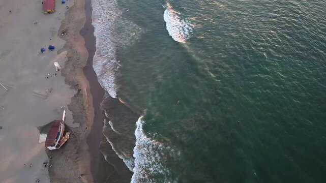 Turquoise waves of South America breaking peacefully on the shores of Manta, while surfers ride the waves, Manabi, Ecuador