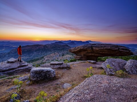 Hiker standing near the Sombrerillo limestone rock formation at dawn, El Torcal nature reserve, Torcal de Antequera, Malaga province, Andalucia, Spain