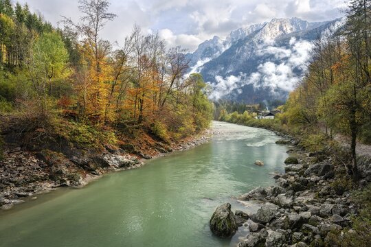 The River Lammer at the end of the Lammerklamm gorge. The Tennengebirge mountains in the background. Trees in autumn leaves. Clouds with some sun. Scheffau, Lammertal, Salzburger Land, Upper Austria, Austria