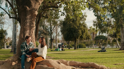 Fototapeta premium Couple Relaxing Under a Tree in Sunny Park