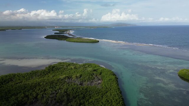 Aerial panorama of La Cobita Beach in Azua featuring shallow turquoise lagoon, mangrove islands, white sand coastline and calm Caribbean ocean filmed in bright daytime