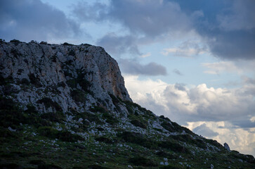 Obraz premium Rocky Mountain Cliff Under Cloudy Sky