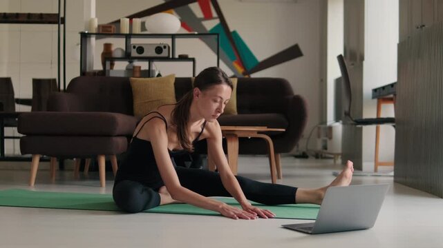 Young Woman Doing Yoga at Home with Laptop