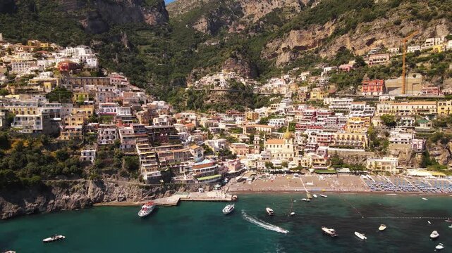 Cinematic aerial view of Positano village on Amalfi Coast in Italy with colorful houses on cliff side.