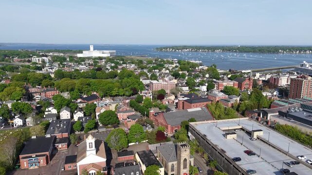 Aerial drone view of Salem Common park and Salem, Massachusetts, showing green grass, walking paths, historic neighborhood houses, and the scenic North River in the background on a sunny summer day