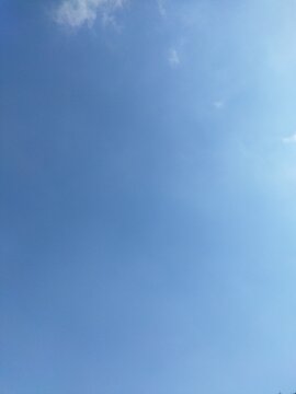 Clear light blue sky background with minimal wispy clouds and empty copy space - vertical view.