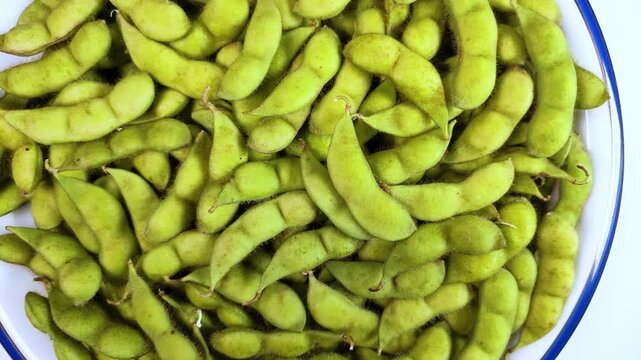 皿に盛った生のだだちゃ豆（枝豆）の回転映像