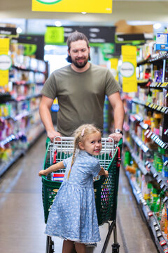 Dad pushing shopping trolley with kid getting groceries