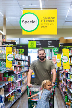 Dad pushing shopping trolley with kid getting groceries