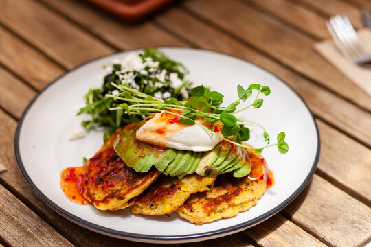 Zucchini Fritters with avocado and sweet chili sauce and green on plate