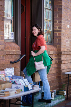 Young woman walking into door of old brick building now a bookstore in country town