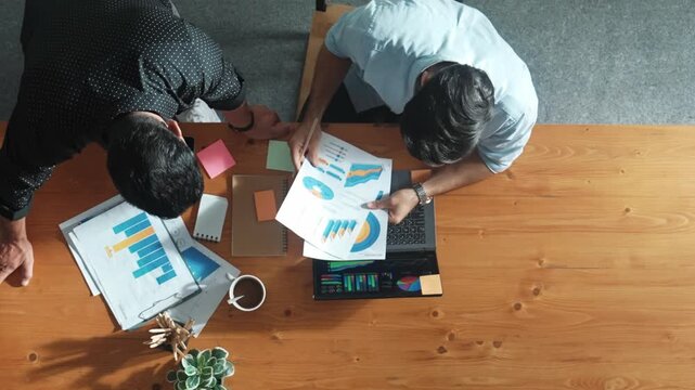 Skilled project manager walking at table while colleague brainstorm idea. Business team working together to plan marketing strategy while looking at data analysis or financial statistic. Convocation.